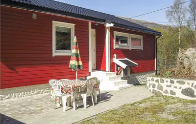 a table and chairs with an umbrella in front of a house at Gorgeous Home In Dalsøyra With Kitchen in Dalsøyra