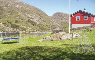 a red house in a field next to a mountain at Gorgeous Home In Dalsøyra With Kitchen in Dalsøyra