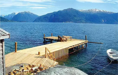 a dock on a lake with a boat on the water at 2 Bedroom Beautiful Home In Balestrand in Balestrand