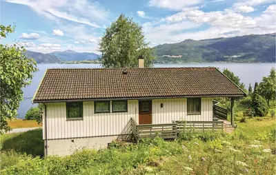 a small white house with a lake in the background at Holiday Home Balestrand Stokkabø in Balestrand