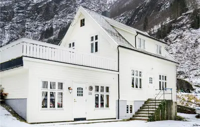 a white house with snowy mountains in the background at Nice Home In Vik I Sogn With Jacuzzi in Åse