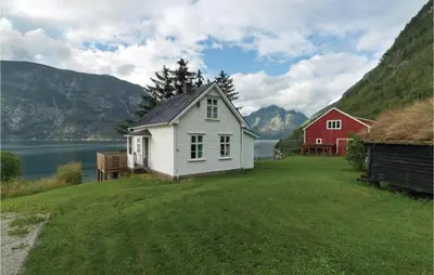 a house and a barn next to a body of water at Naddvik in Årdalstangen