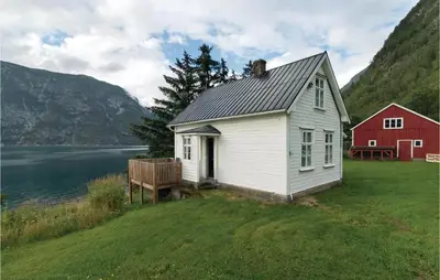 a white house and a red barn next to a body of water at Naddvik in Årdalstangen