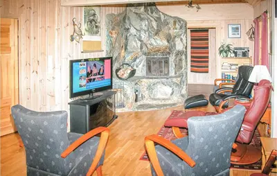 a living room with chairs and a tv and a rock wall at Stunning Home In Sogndal With Sauna in Sogndal