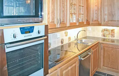 a kitchen with wooden cabinets and a stove and a sink at Stunning Home In Sogndal With Sauna in Sogndal