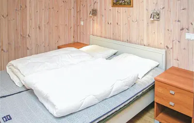 a white bed in a room with a wooden wall at Stunning Home In Sogndal With Sauna in Sogndal