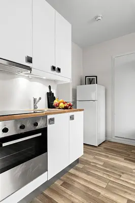 a kitchen with white cabinets and a sink and a refrigerator at Central and quiet studio apartment in Ålesund in Ålesund