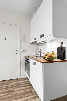a kitchen with white cabinets and a bowl of fruit on a counter at Central and quiet studio apartment in Ålesund in Ålesund