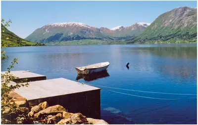 a boat in the middle of a lake with mountains at Beautiful Home In Skei I Jølster in Årdal