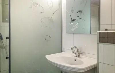 a bathroom with a sink and a shower with drawings on the wall at Holiday Home Måløy Husevåg in Måløy