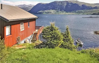 a house on the side of a lake with a boat at 3 Bedroom Awesome Home In Måløy in Måløy
