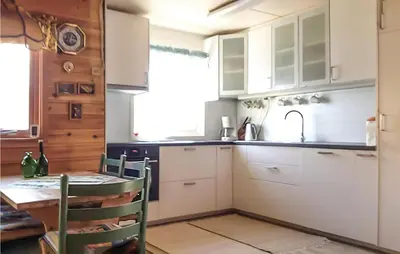 a kitchen with white cabinets and a table and a sink at 3 Bedroom Awesome Home In Måløy in Måløy
