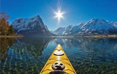 a person in a kayak on a lake with mountains at Glomnes Nr 2 in Hjelle