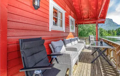a red house with chairs and a table on a deck at 3 Bedroom Amazing Home In Sandane in Sandane