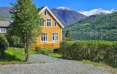 a wooden house with a lake and mountains in the background at Amazing Home In Olden With Wifi in Olden