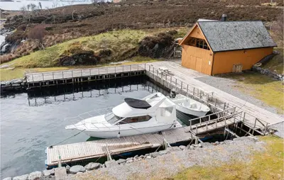 a boat docked at a dock next to a building at Holiday Home Kvamsøy Storholmen in Sandvik