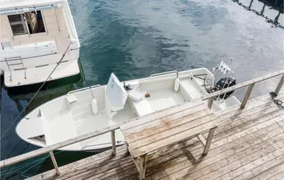 a boat tied up to a dock with a bench at Holiday Home Kvamsøy Storholmen in Sandvik
