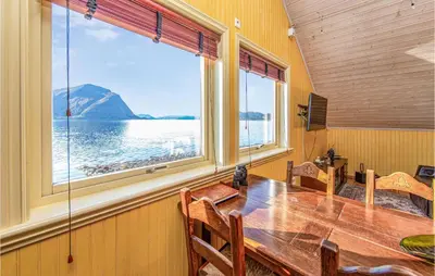 a dining room with a table and a large window at Beautiful Home In Hundeidvik in Hundeidvik