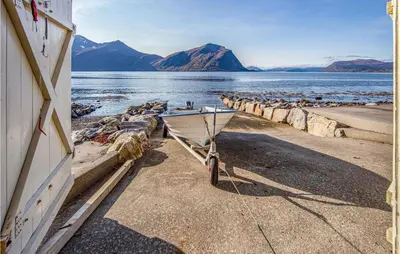 a boat parked on a beach next to the water at Beautiful Home In Hundeidvik in Hundeidvik