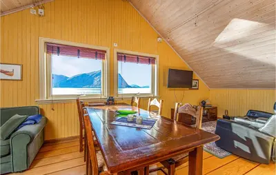 a dining room with a table and a couch at Beautiful Home In Hundeidvik in Hundeidvik