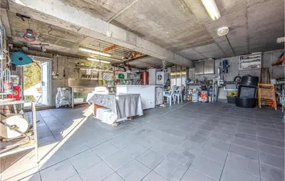 a garage with a room with a table and a kitchen at Beautiful Home In Hundeidvik in Hundeidvik