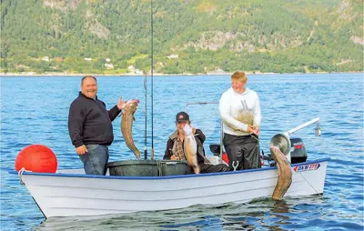 a group of men standing in a boat on the water at Hytte 19 in Ikornnes