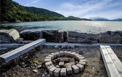 a fire pit next to a body of water at Hytte 19 in Ikornnes