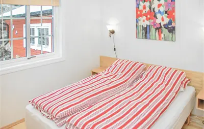 a striped blanket on a bed in a room with a window at 4 Bedroom Beautiful Home In Hundeidvik in Hundeidvik