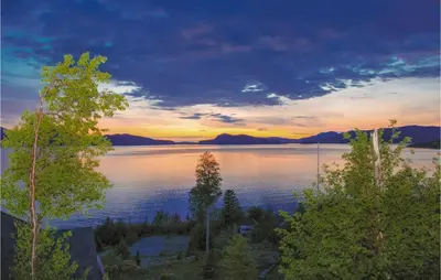 a view of a lake with a sunset in the background at 4 Bedroom Beautiful Home In Hundeidvik in Hundeidvik