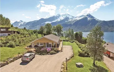 a car parked in front of a house with mountains at Gorgeous Home In Hundeidvik in Hundeidvik