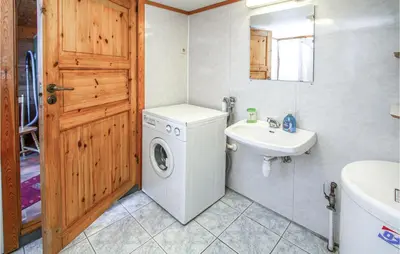 a bathroom with a washing machine and a sink at Holiday Home Vågstranda Hjelvik Ii in Hjelvik