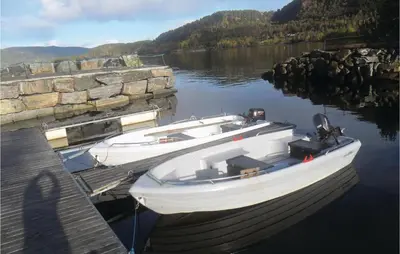 two boats are docked at a dock on a lake at Holiday Home Vågstranda Hjelvik Ii in Hjelvik