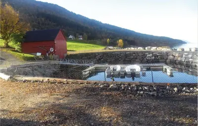 a pool of water with a red barn and a building at Holiday Home Vågstranda Hjelvik Ii in Hjelvik