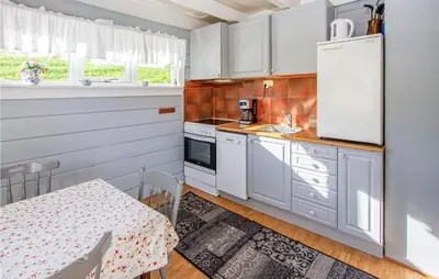 a small kitchen with white cabinets and a table at Holiday Home Vågstranda Hjelvik Ii in Hjelvik