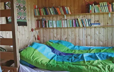 a bed in a wooden room with a book shelf at Idavolden in Stangvik