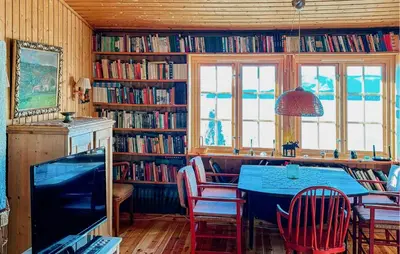 a dining room with a blue table and chairs and book shelves at Idavolden in Stangvik