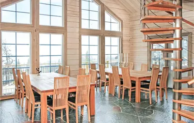 a dining room with a table and chairs and windows at Amazing Home In Trysil With Sauna in Trysil