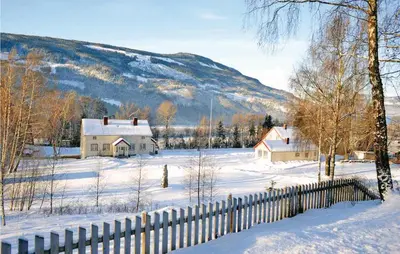 a house in a snow covered field with a fence at Amazing Home In Ringebu in Ringebu