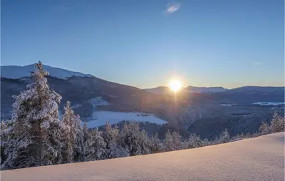 a snow covered hill with the sun rising over a lake at Holiday Home Heidal Bakketun in Heidal