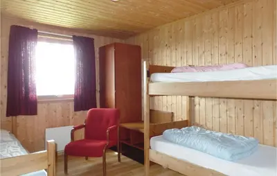 a room with two bunk beds and a red chair at Storhytta in Vinstra