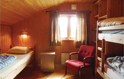 a bedroom with a bed and a chair and a window at Storhytta in Vinstra