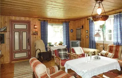 a living room with wooden walls and a table and chairs at Kveldsro in Eina