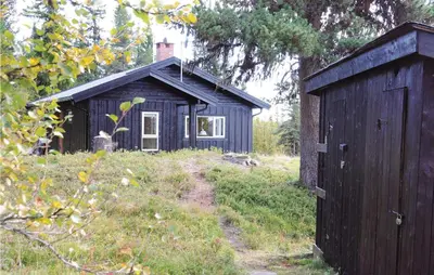a small black building in the middle of a field at Trollbu Granåsenfefor in Vinstra