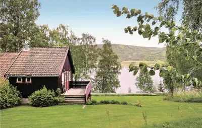 a small house on a lawn next to a lake at Lovely Home In Vestsida With Wifi in Fall