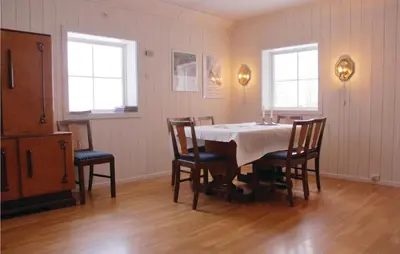 a dining room with a table and chairs and two windows at Lovely Home In Vestsida With Wifi in Fall
