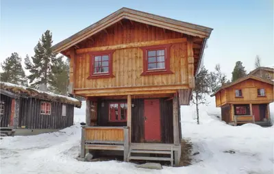 a wooden cabin with red doors in the snow at Holiday Home Ringebu Måsåplassen Ii in Ringebu