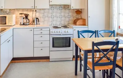 a kitchen with white appliances and a wooden table at Holiday Home Hunndal Skumlivegen