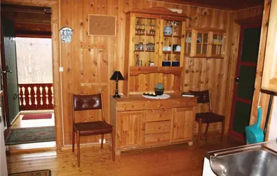 a kitchen with a wooden cabinet and two chairs at Thorleifsbuskogheim in Vang I Valdres