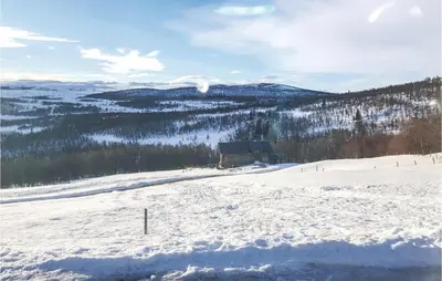 a snow covered hill with a building in the distance at Tallåsen Dagalifjell in Uvdal