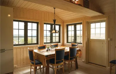 a kitchen with a wooden table and chairs and windows at Tallåsen Dagalifjell in Uvdal